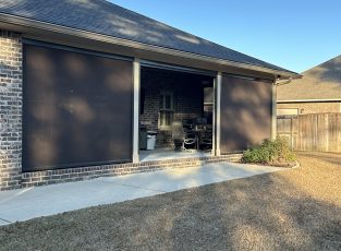 Exterior view of motorized retractable patio screens installed on a covered outdoor living space providing shade, privacy, and insect protection